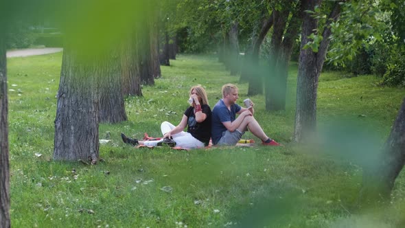 Mother and Adult Son Rest and Drink Tea in Park