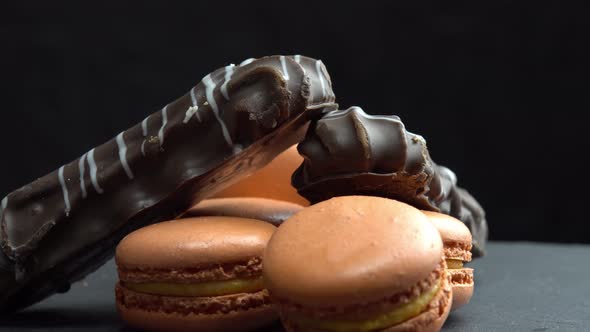 Chocolate and Macaroon Rotate on a Black Background and the Hand Takes Candy Sweets are Spinning