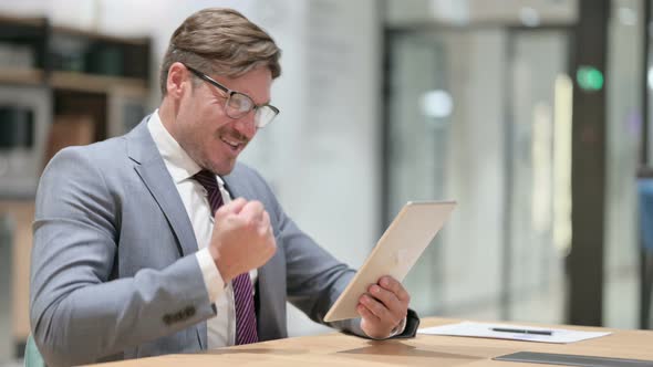 Successful Businessman Celebrating on Tablet in Office