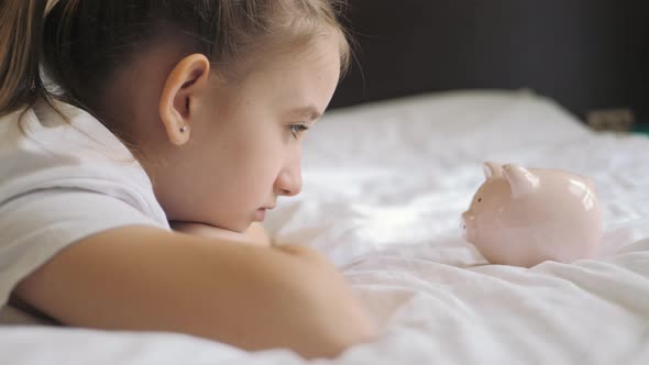 Girl Putting Coin in Piggy Bank Saving Money Concept