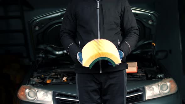 Car mechanic in car service bends in the hands of the car air filter