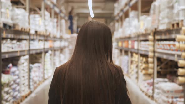 Woman choosing some stuff in hardware store. Pushing shopping cart buying materials in house improve