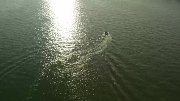 Surrounded by water and the light of the setting sun, a motorboat roams.