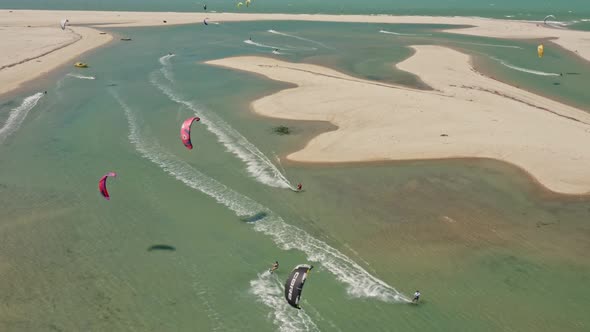 Several kite surfers sailing close jumping in shallow green Brazil pond on beach