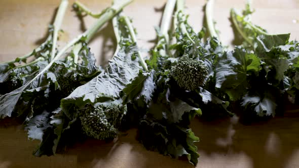 Clusters of rapini on a wood cutting board ready for chopping. Slide from left to right.
