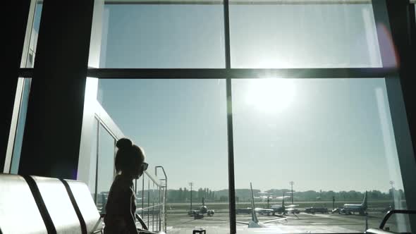 Little Child Girl Waiting for a Plane Sit at Airport Passenger Terminal Gates Panoramic Windows