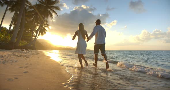 Young People Running Hand in Hand on Sunset Having Romantic Evening Near Ocean Enjoy Time Together