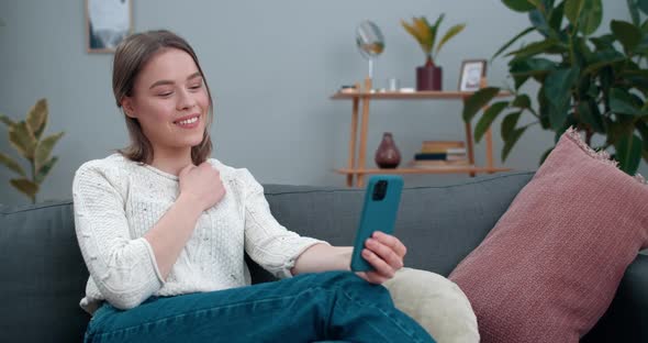 Happy Woman Showing with with Deaf-mute Sign Language Phrase I Love You While Sitting on Couch