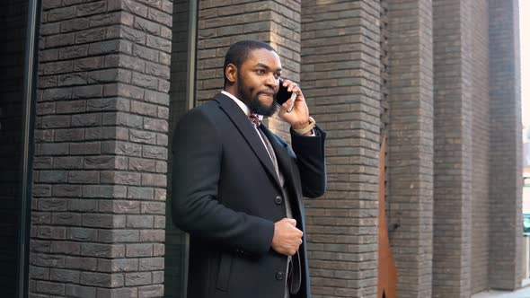 Young Elegant African Businessman Talking on Phone Near the Office Center