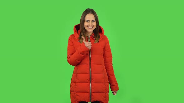 Lovely Girl in a Red Down Jacket Is Showing Thumbs Up, Gesture Like. Green Screen