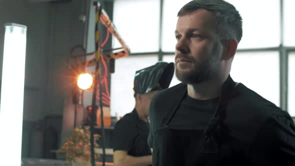 Factory worker puts on a protective coat and goes to his machine. Close-up. Portrait