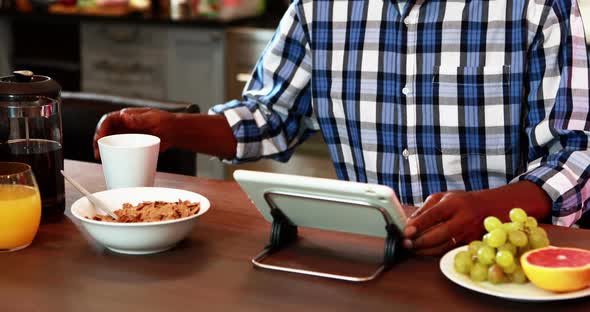 Smiling senior man using digital tablet while having breakfast