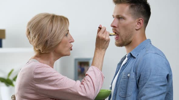 Patient Man Submissively Eating With Spoon to Please His Mother, Relationship