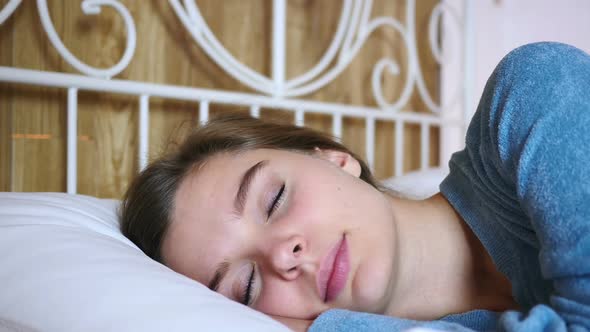 Close Up of Smiling Young Woman Looking at Camera in Bed
