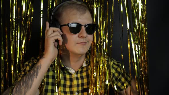 Portrait of Caucasian Man Dancing on Black Background. Gold Shining Foil Strips. Party, Music, Disco