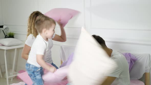 Young Family Mom Dad and Little Son are Having Fun Pillow Fight on Bed