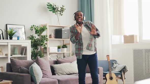 Handsome African American Guy Is Dancing and Singing Listening To Music Through Headphones in Light