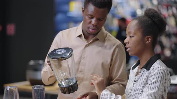 Black Man and Woman are Buying Equipment for Kitchen in Home Appliances Store Discussing Exhibition