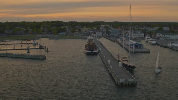 Aerial Pan of a Neighborhood by the Water and Docked Boats at a Marina at Sunset