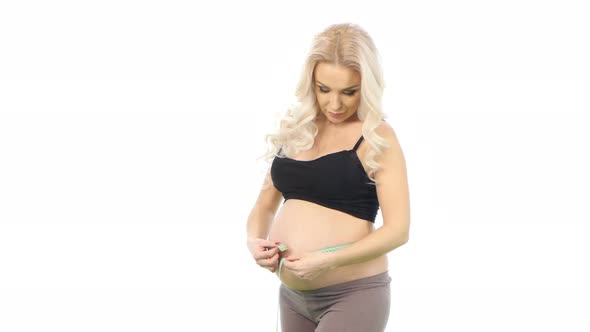 Pregnant Woman Measures Her Tummy By Tape Measure, White