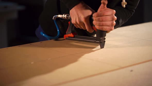 Close Up Shot of a Man's Hands, Who Uses Carpentry Stapler in Creating Furniture