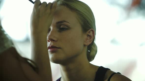 Makeup artist applying face powder on womens face