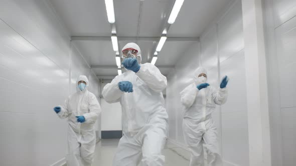 Team of Medical Workers in Hazmat Suits Dancing and Walking in Hospital Corridor