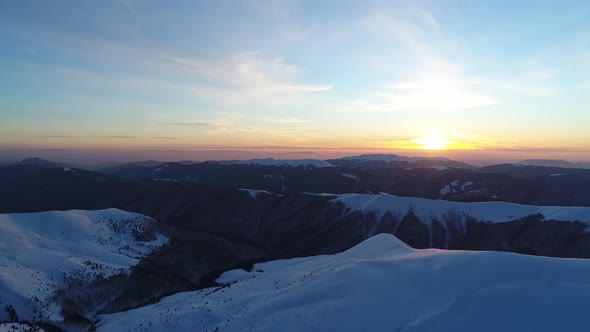 Flight over the snowy mountains illuminated by the evening sun