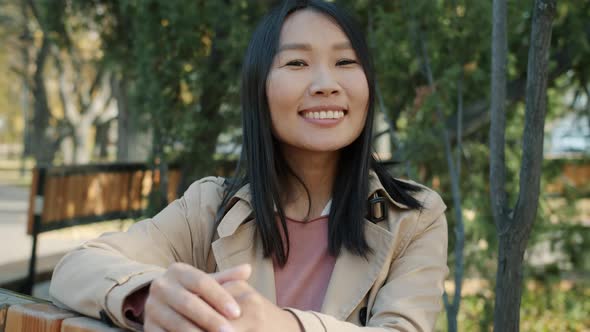 Slow Motion Portrait of Joyful Asian Business Lady Smiling Outdoors Against Autumn Trees Background