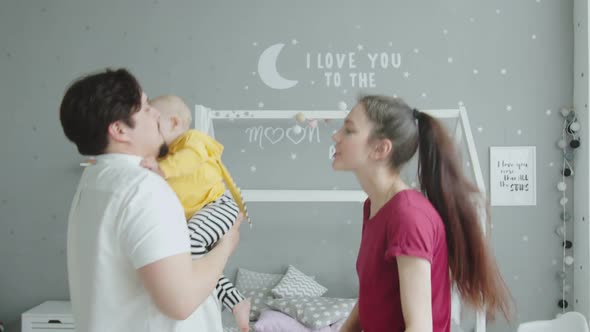 Joyful Parents Dancing with Infant Girl in Bedroom