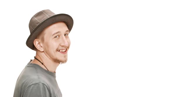 Young Handsome Man in Hat Smiling Passing By Over White Background