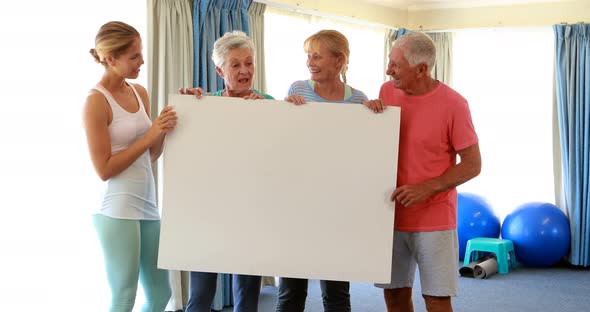 Trainer and senior citizens holding empty placard