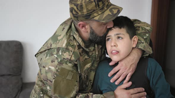 Military soldier kissing his son with disability at home