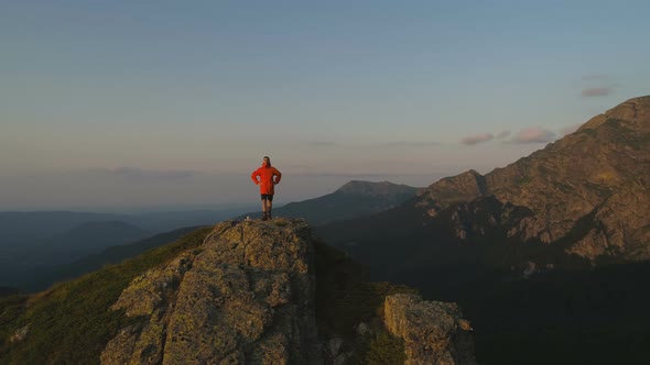 Single Hiker on Rocky View Point Above Deep Green Valley Looking the Sunset