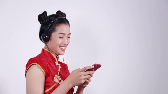 happy woman wear cheongsam and using mobile phone to listening music with headphone