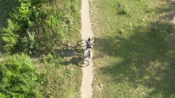 A young couple rides a tandem two-seater bike along the riverbank