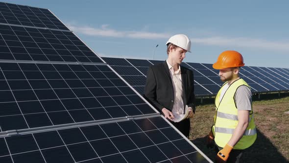 Businessman and Worker Are Checking Solar Batteries Together Outside