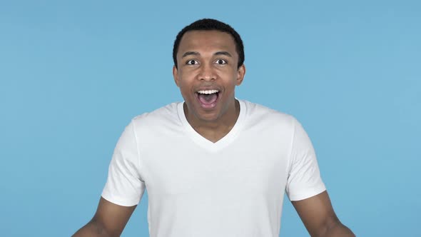 Happy Amazed Young African Man Surprised By Gift Blue Background