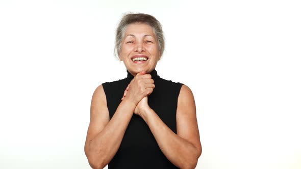 Elder Wrinkled Woman with White Tied Hair Looking at Camera with Beautiful Smile Clenching Her Hands