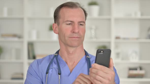 Portrait of Focused Middle Aged Doctor Using Smartphone 