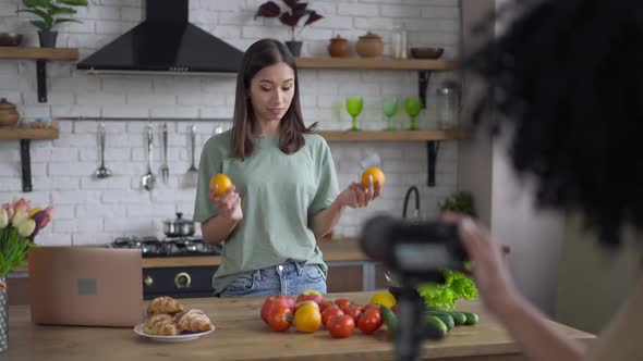 Gorgeous Smiling Slim Asian Woman Talking at Video Camera in Kitchen Showing Ingredients of