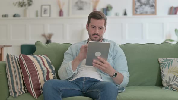 Young Man Using Tablet on Sofa