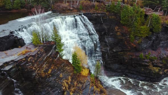 Waterfall, rock ledge and tree among green in Kaministiquia River, Kakabeka Falls, Ontario, Canada