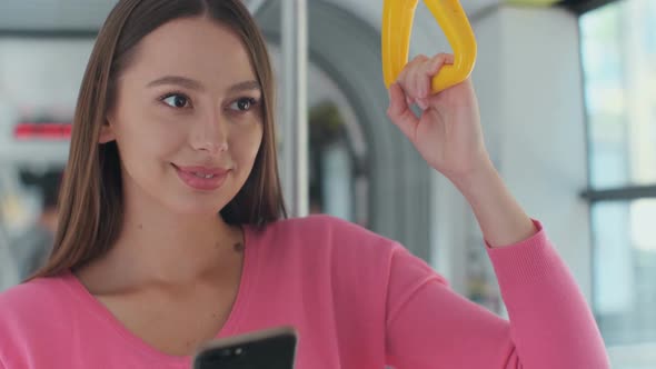 Close-up Portrait of a Young Woman Using Smartphone While Standing in the Modern Tram.