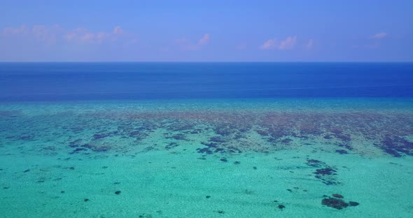 Wide angle fly over copy space shot of a sandy white paradise beach and aqua blue ocean background i