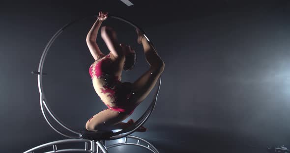 Young Woman in Red Costume is Spinning on a Steel Hoop Doing Gymnastics