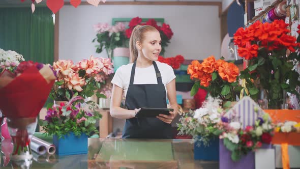 Florist Woman Takes Inventory in a Flower Shop a Female Uses a Screen Tablet to Count the Number