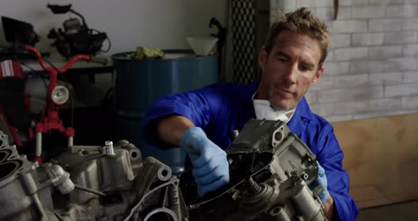 Male mechanic repairing motorbike parts in repair garage 4k