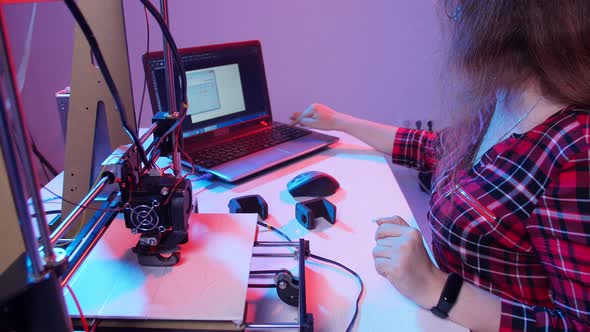 Concept of Modern Production Technologies. Young Woman Student Makes the Item on the 3D Printer