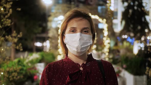 Portrait of cute female at night. Happy tourist in medical mask after quarantine at the street city.